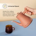 Een hand giet water uit de terracotta waterkoker met universele tuit in een bruine mok. Perfect voor koffie, thee en meer.