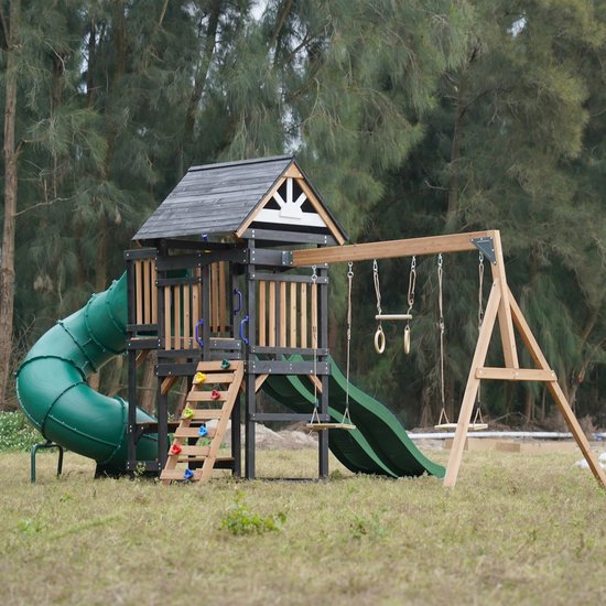 Houten speeltoestel met groene buisglijbaan, dubbele groene glijbaan, schommels, trapeze en klimwand.