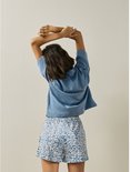 Model met rug naar ons toe, draagt blauw shirt en korte pyjamabroek met bloemenprint.