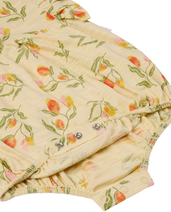 Detail van baby broekje met bloemenprint in geel, knoopsluiting aan de onderkant.
