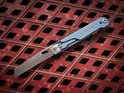 Blauw Black Eagle multitool mes met lichtblauwe handgreep, opengeklapt op rood rasteroppervlak.