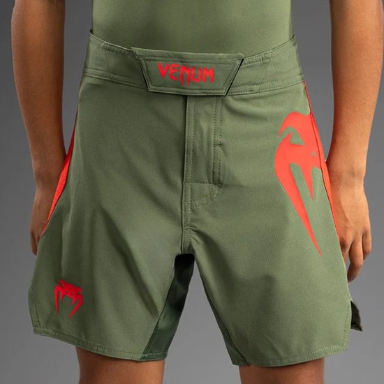 Dichtbij opdruk van de tailleband van een groene vechtsportbroek met 'VENUM' en logo.