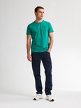 Man draagt een groene t-shirt met tekst en donkerblauwe cargobroek met opgestikte zakken.