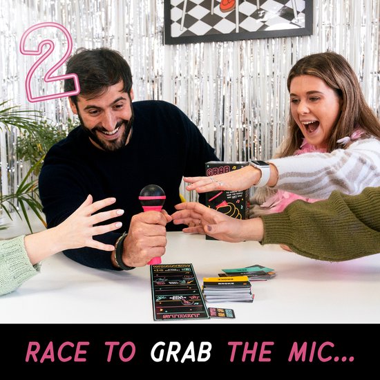 Mannen en vrouwen spelen een spel waarbij ze naar een roze microfoon grijpen.
