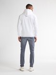 Man van achteren gezien, draagt een witte hoodie en grijze slim fit jeans. Witte sneakers.