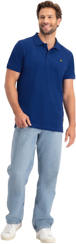 Man met zandkleurig haar in een blauw NOMAD poloshirt met korte mouwen en jeans.
