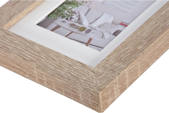 Détail du coin d'un cadre photo en bois brun clair avec grain de bois.