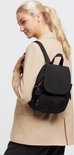 Vrouw in beige blazer draagt een zwarte Kipling rugzak.