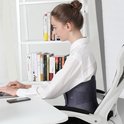 Vrouw met een donkerblauwe rugbrace om op haar laptop te typen. De brace bedekt de onderrug.