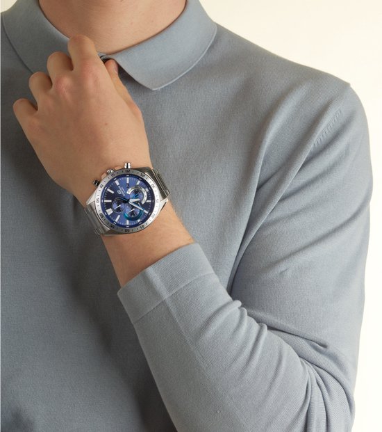 Herenhorloge met zilverkleurige metalen band en blauwe wijzerplaat. Gedragen door een model in een grijs poloshirt.