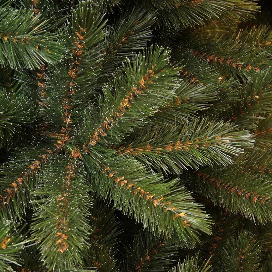 Gedetailleerd close-up van groene kerstboomtakken met fijne witte puntjes.