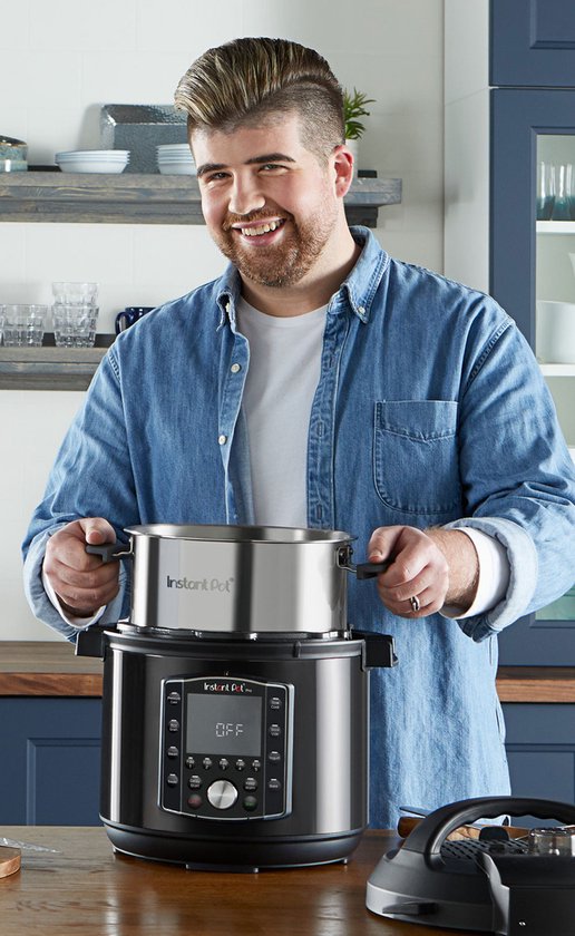 Een man met spijkerjas tilt een RVS binnenpan uit de Instant Pot multicooker.
