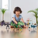 Een jongen zit op de vloer met drie Eldrador Creatures speelgoeddraken: een groene met gele klauwen, een zwarte met paarse vleugels en een blauw met witte ijsvleugels.