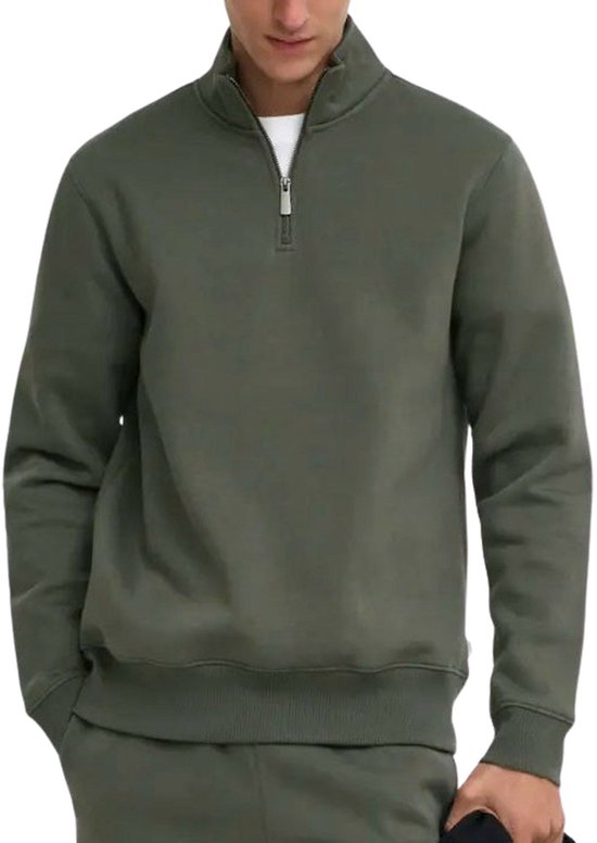 Man in donkergroene sweater met halve rits en hoge kraag.