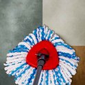Spinmopkop met rode houder, witte en blauwe vezels, op een betegelde vloer.
