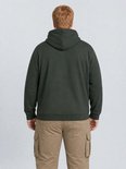 Achterkant van een man met rode baard in een donkergroene hoodie en beige cargobroek.