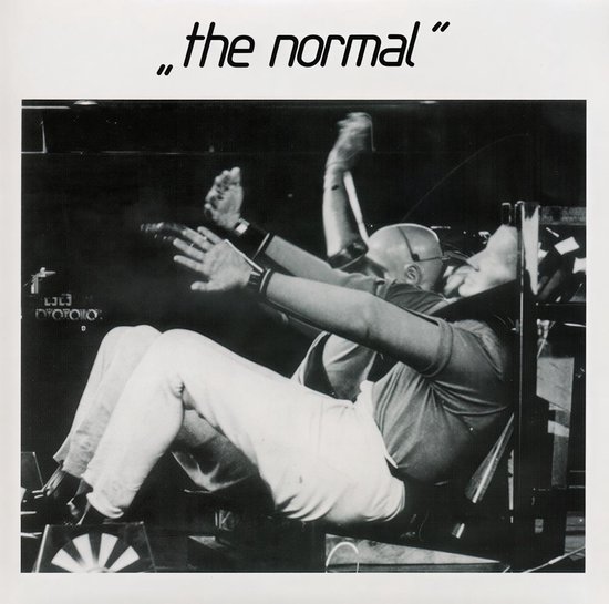 Titel van de single "the normal". Mannen in stoelen met hun armen omhoog.
