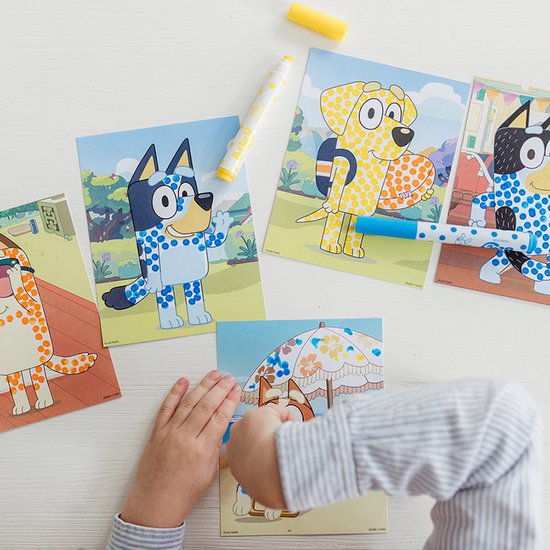 Kind stippelt met een blauwe stempelstift op een Bluey kaart met een hond bij een zwembad.