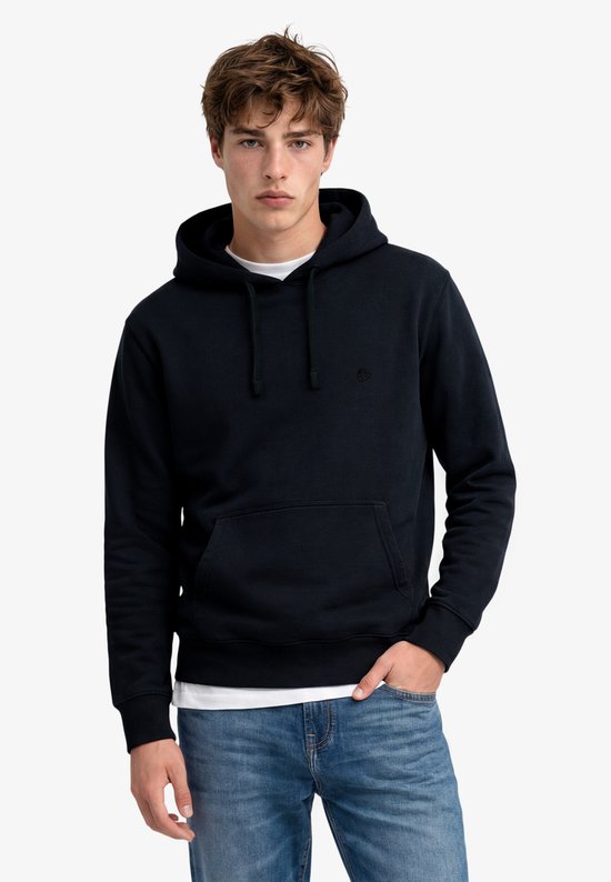 Model met donkerblauwe hoodie met capuchon, kangoeroezak en jeans.