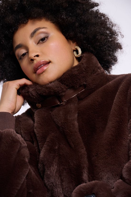Close-up van het gezicht van een model met een bruine Faux Fur bomberjack met een hoge kraag en leren sluitingen.