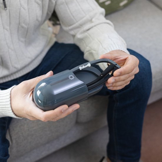 Man houdt een AYOlite lichttherapiebril in een opbergdoosje vast. Stijlvol en compact opbergen.