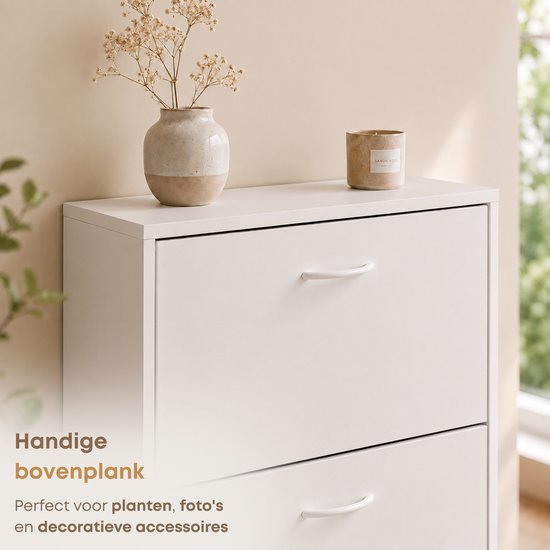 Commode blanche à trois tiroirs avec vase décoratif, bougie et plante.