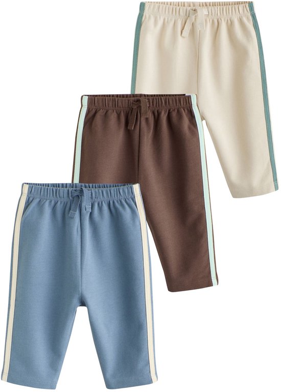Drie babyjoggingbroeken (blauw, bruin, crème) gestapeld.