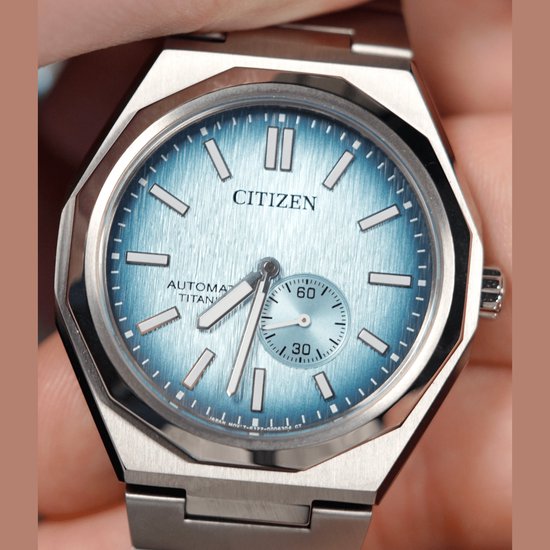 Close-up van een Citizen horloge met lichtblauwe wijzerplaat, gedragen op een hand. Zilverkleurige titanium kast en band.