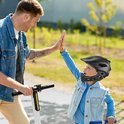 Zwarte kinderhelm op een lachende jongen die een high five geeft.
