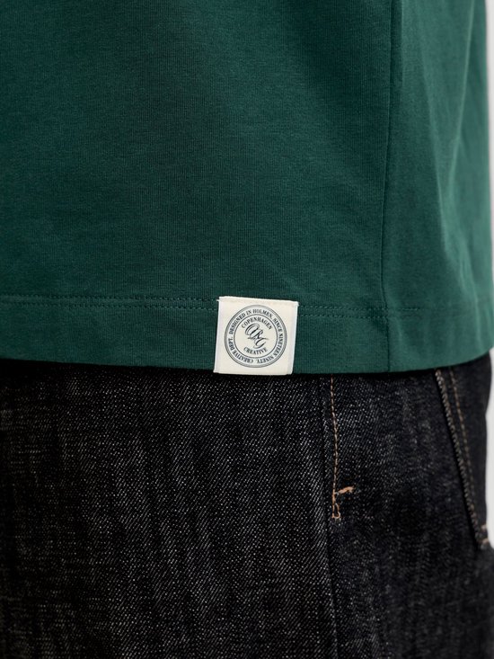 Detail van een donkergroen T-shirt van Jack & Jones met een rond label met logo en tekst 'DESIGNED IN HOLMEN. COPENHAGEN. CREATIVE DEPT.'