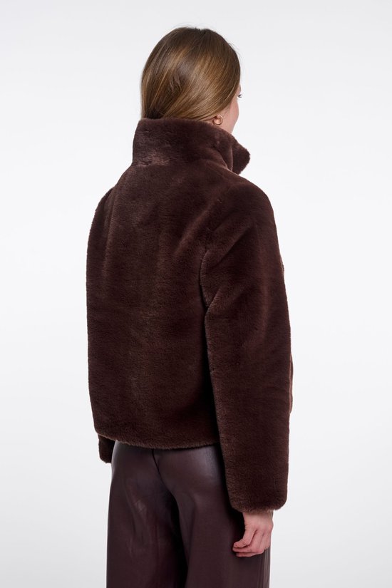 Achterkant van een model die een korte, bruine faux fur jas draagt met een hoge kraag.