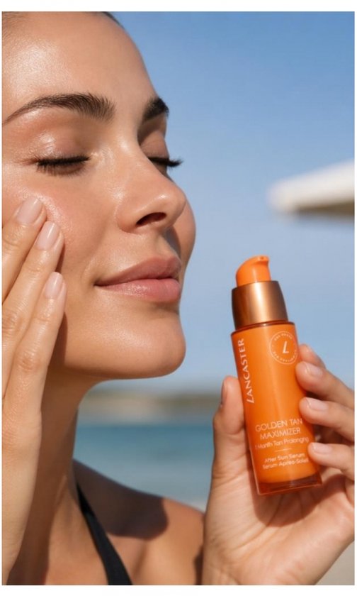 Vrouw met gebruinde huid brengt Lancaster Golden Tan Maximizer serum aan, met strand op de achtergrond.