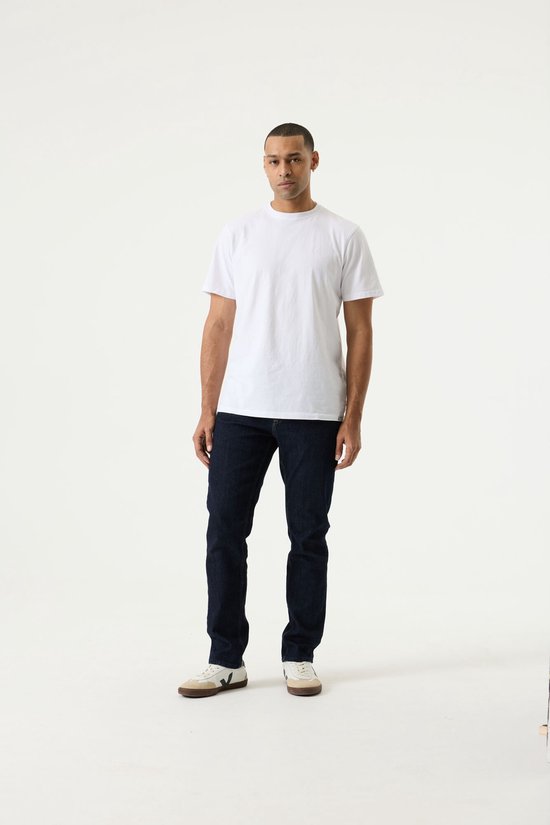 Man met donkere spijkerbroek en witte t-shirt.