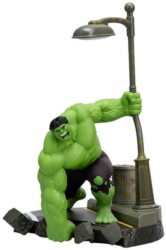 Hulk, vert et musclé, s'accroche à un lampadaire au-dessus d'une scène de rue avec des débris.