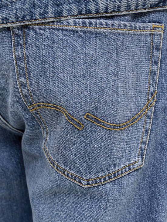 Detail van de achterzak van een spijkerbroek met gele sierstiksels.