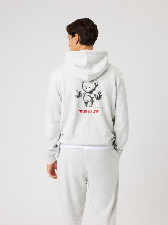 Lichtgrijze hoodie voor heren met aan de achterkant een teddybeer die een halter optilt, met de tekst 'TRAIN TO LIVE'.