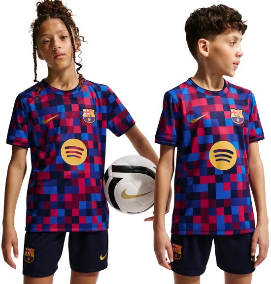 Twee kinderen dragen FC Barcelona shirts met een rood, blauw en marineblauw blokkenpatroon. Meisje met vlechtjes houdt voetbal vast.