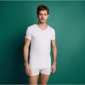 Man met wit t-shirt met V-hals en boxer, tegen groene achtergrond.