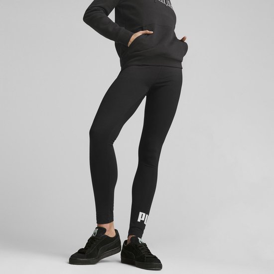 Close-up van een vrouw die zwarte Puma leggings draagt met witte letters op de zijkant van de pijpen.