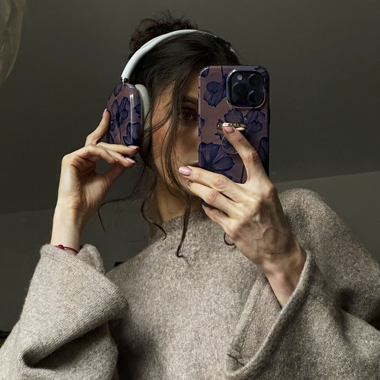 Vrouw met koptelefoon en telefoonhoesje in bijpassend design met paarse bloemen.