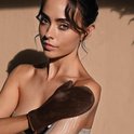Model met getinte huid brengt bruinende mousse aan op arm met een handschoen.