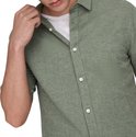 Detail van een groen, kortarmig hemd met witte knopen en een witte T-shirt.