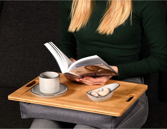 Plateau de lit en bois avec coussin gris, avec une tasse, une soucoupe et un bol à biscuits.