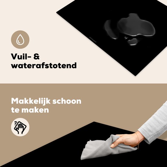 Zwarte inductiebeschermer, met water erop, en een hand die hem schoonmaakt.