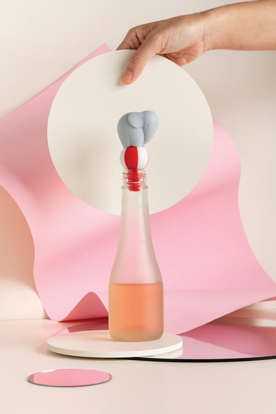 Hand plaatst grijze olifant wijnstopper op een fles, met roze papierdecoratie.