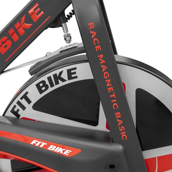 Close-up van het vliegwiel van een spinfiets met de tekst "FIT BIKE" en "RACE MAGNETIC BASIC".