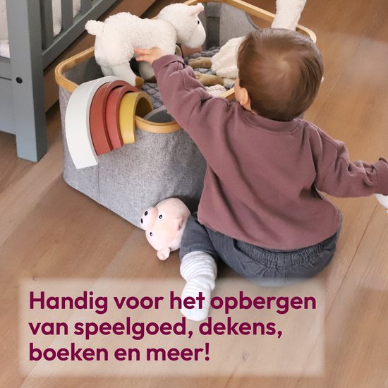 Baby die speelgoed uit een grijze wasmand met bamboe rand pakt.