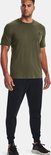 Man met olijfgroene korte mouw shirt en zwarte joggingbroek.