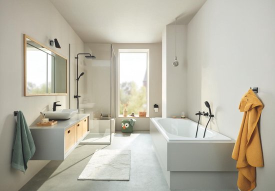 Moderne badkamer met douche, ligbad, wastafel en een matzwarte toiletrolhouder bij de toiletruimte.