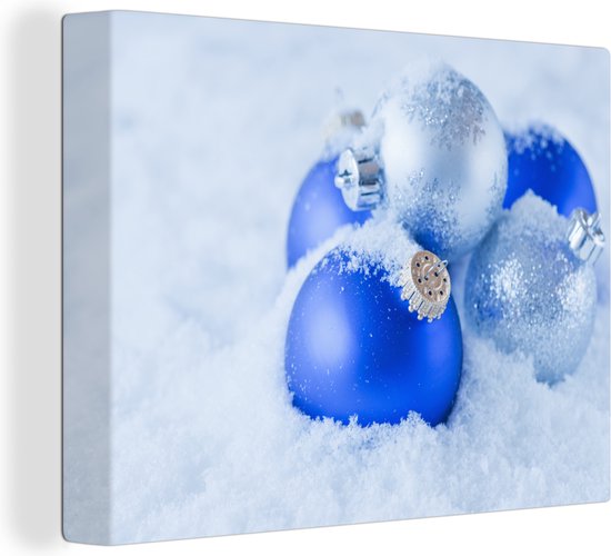 Canvas Schilderij Een set blauwe en zilveren kerstballen bevinden zich in de sneeuw - 80x60 cm - Wanddecoratie